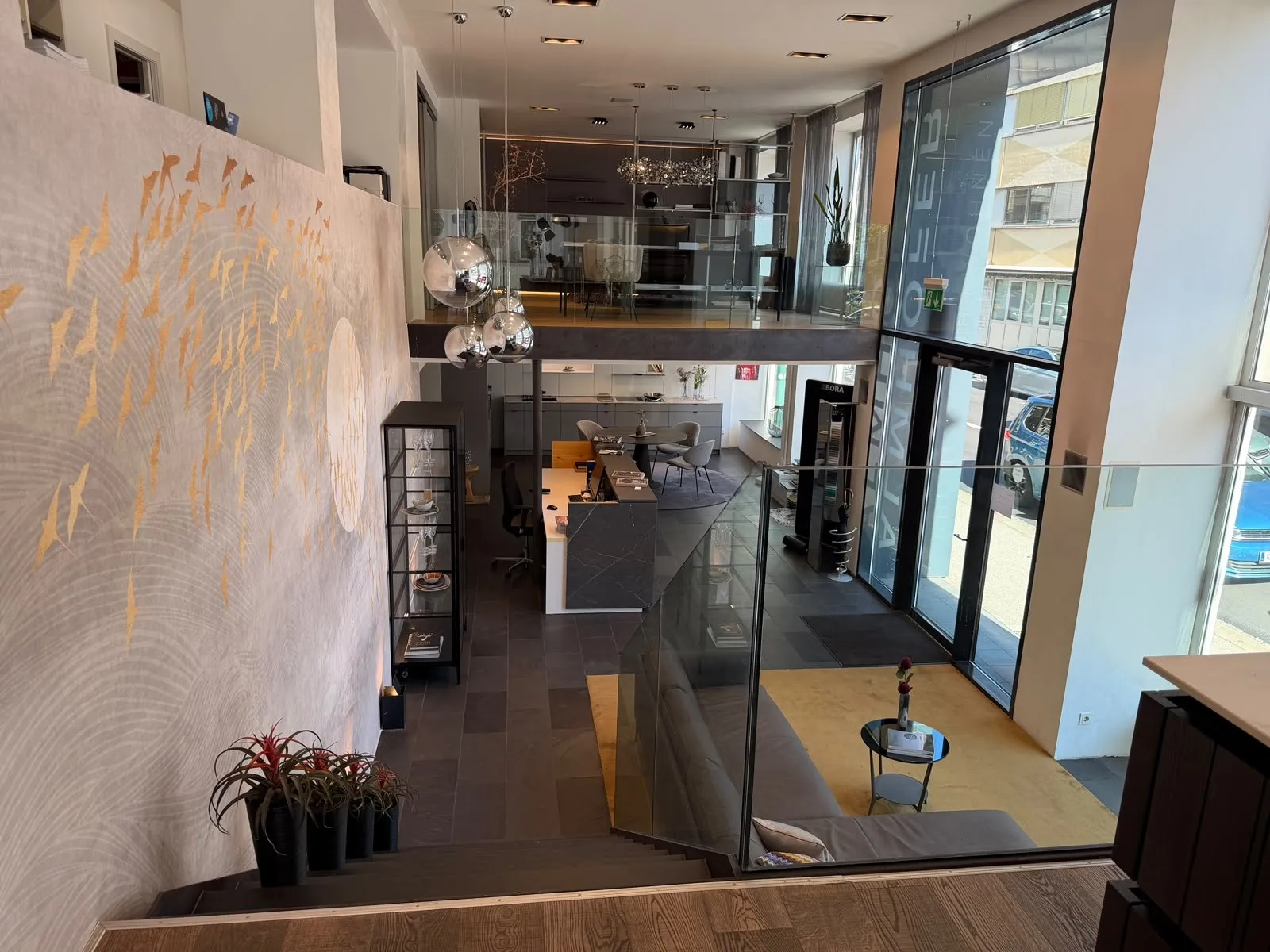 Blick von der Galerie hinunter in den Schauraum mit Empfang, Sofa und Küche